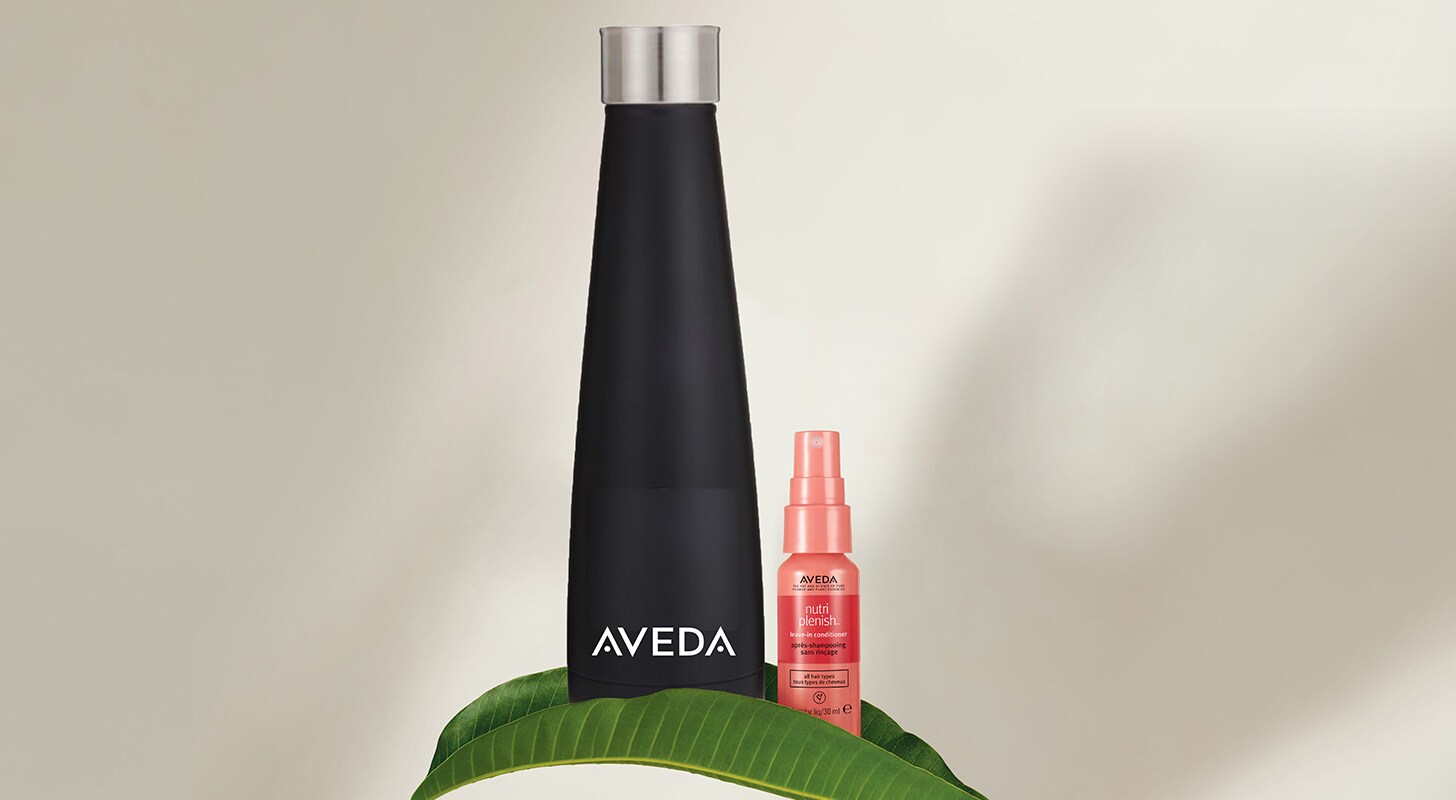 aveda water bottle and nutriplenish leave-in conditioner mini and leaf on beige background